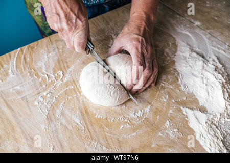 Ältere Frau Bäcker schneiden Teig in Home Küche Stockfoto