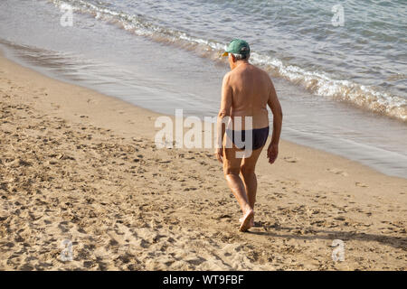 Ansicht der Rückseite des alten Mann zu Fuß am Strand. Stockfoto