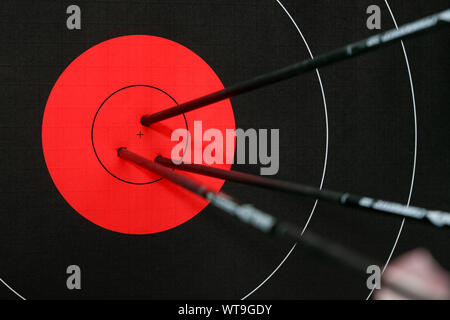 Drei Pfeile in der Mitte der schwarzen und roten Bogenschießen Ziel. Genauigkeit und Präzision. Stockfoto