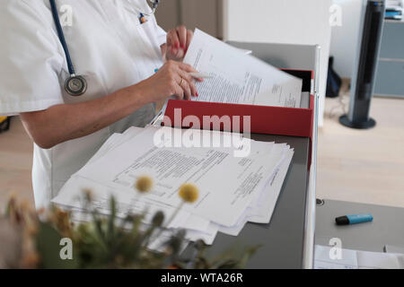 Arzt sortieren heraus Schreibarbeit an ihrem Schreibtisch Stockfoto