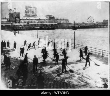 Männer Schnee von Clearing Promenade, Atlantic City, New Jersey, am Ostersonntag; Steeplechase Pier in backgrd. Stockfoto