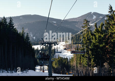 Bukovel, Ukraine. 2, 2017 einen Aufzug für Skifahrer und Snowboarder steigt auf den Gipfel des Berges. Um eine Menge Schnee und Bäume. Skigebiet komplexe Buko Stockfoto