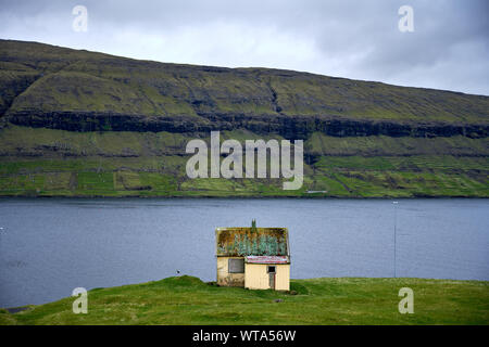 Schäbig Bauen auf der grünen Wiese auf der hohen Küste neben Cliff in bewölkten Tag Stockfoto