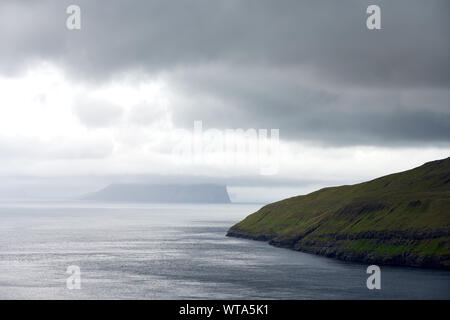 Dunkle Wolken Himmel über noch Meer Wasser mit majestätischen Scenic green Klippen an der Küste Stockfoto