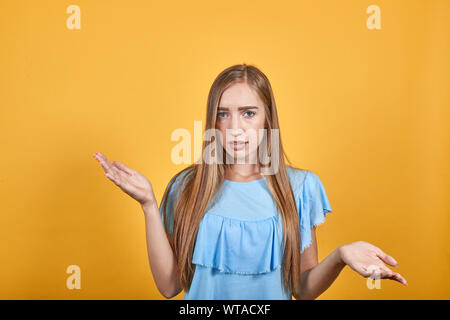 Mädchen Brünette in blauen T-Shirt über isolierte orange Hintergrund zeigt Emotionen Stockfoto