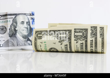 Leicht gewellte Ein-Dollar-Scheine auf einen hellen Hintergrund. Im Hintergrund, Präsident Franklin auf einem 100-Dollar Bill. Reflexion der Noten auf einem Stockfoto