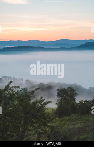 Blick auf den Sonnenaufgang über den Bergen Nebel und Wolken unter Spitzen Stockfoto