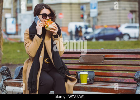 Junge Schönheit Business woman Essen fast food und Arbeiten am Telefon während der Sitzung im City Bank Stockfoto