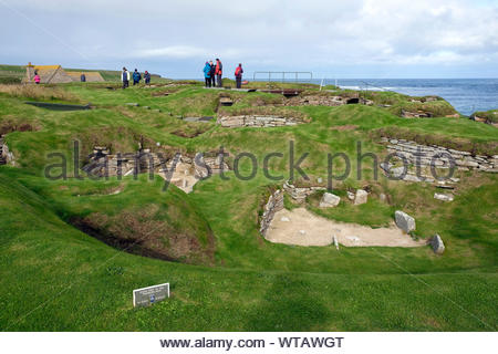 Touristen, die in Skara Brae, eine jungsteinzeitliche Siedlung aus Stein, auf dem Festland von Orkney, Schottland entfernt Stockfoto