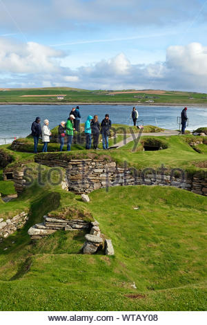 Touristen, die in Skara Brae, eine jungsteinzeitliche Siedlung aus Stein, auf dem Festland von Orkney, Schottland entfernt Stockfoto