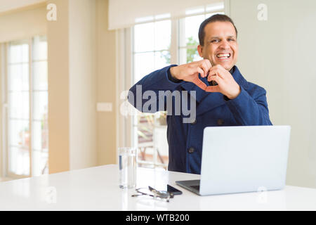 Mittleres Alter business Mann arbeitet mit Laptop in der Liebe mit Herz und mit Hand lächelnd. Romantische Konzept. Stockfoto