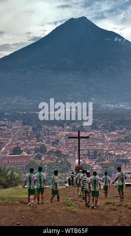 Guatemala, August 2019: Blick vom Cerro de la Cruz auf Antigua. Fußball-Spieler Training cardio vor Kreuz mit Vulkan Agua. Stockfoto