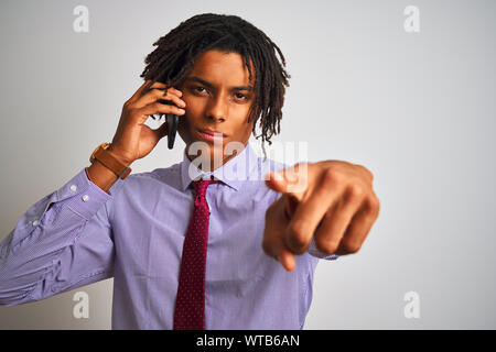 Afro Geschäftsmann mit Dreadlocks sprechen mit Smartphone über isoliert weißer Hintergrund mit dem Finger an die Kamera und an Sie gerichtet, Handzeichen, pos Stockfoto