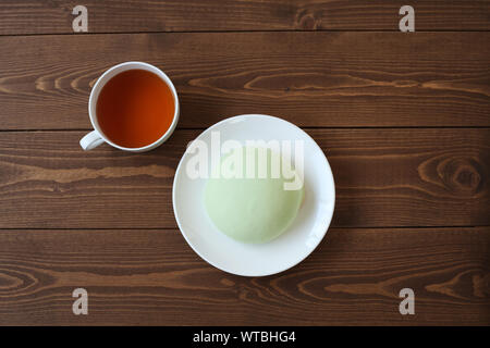 Grüne runde Melone pan auf Platte mit heißem Tee closeup auf Holztisch, isoliert Stockfoto