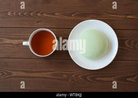 Grüne runde Melone pan auf Platte mit heißem Tee closeup auf Holztisch, isoliert Stockfoto
