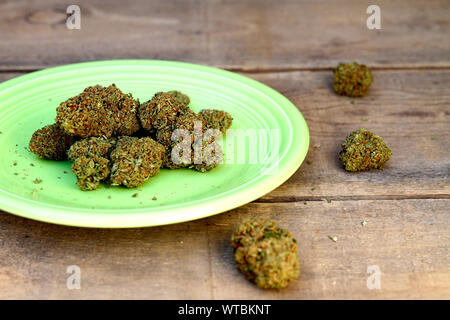 Marihuana Knospen auf der Grünen Platte und Holz Hintergrund Stockfoto
