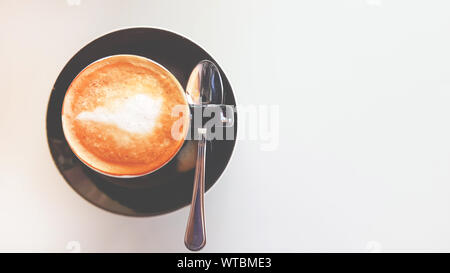 Blick von oben auf die Kaffee Latte, Cappuccino Cup am weißen Tisch in vintage Farbton Konzept. Stockfoto
