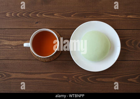 Grüne runde Melone pan auf Platte mit heißem Tee closeup auf Holztisch, isoliert Stockfoto