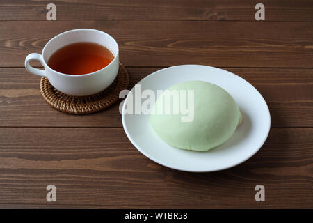 Grüne runde Melone pan auf Platte mit heißem Tee closeup auf Holztisch, isoliert Stockfoto