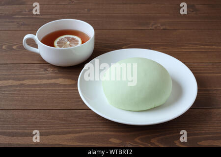 Grüne runde Melone pan auf Platte mit heißem Tee closeup auf Holztisch, isoliert Stockfoto