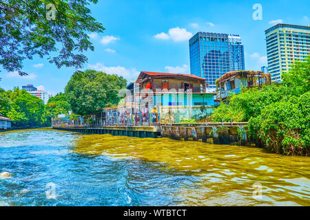 Das alte Holz Wohnhäuser entlang der Bank von KHLONGS von Bangkok Nachbarn mit hoch modernen Bauten der Geschäftsviertel der Stadt, Thailand Stockfoto