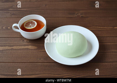 Grüne runde Melone pan auf Platte mit heißem Tee closeup auf Holztisch, isoliert Stockfoto