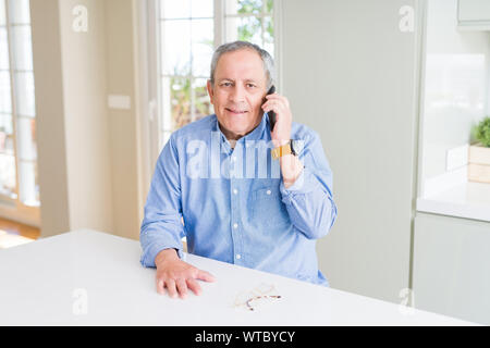 Gut aussehender älterer Mann ein Gespräch sprechen auf dem Smartphone mit einem glücklichen Gesicht stehen und lächelnd mit einem selbstbewussten lächeln zähne Stockfoto