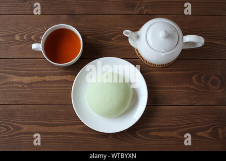 Grüne runde Melone pan auf Platte mit heißem Tee closeup auf Holztisch, isoliert Stockfoto