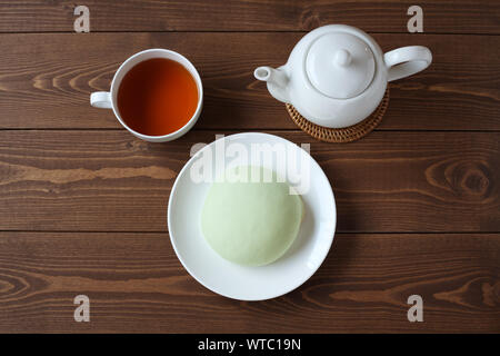 Grüne runde Melone pan auf Platte mit heißem Tee closeup auf Holztisch, isoliert Stockfoto