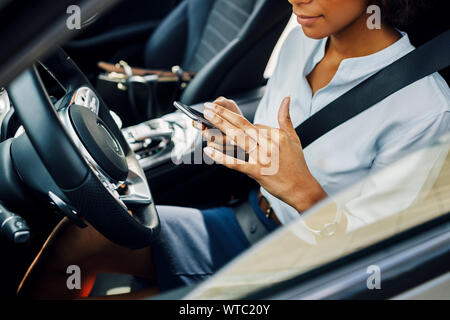 Nicht erkennbare Frau mit Smartphones im Auto sitzen. Stockfoto