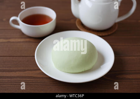 Grüne runde Melone pan auf Platte mit heißem Tee closeup auf Holztisch, isoliert Stockfoto