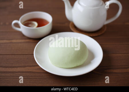Grüne runde Melone pan auf Platte mit heißem Tee closeup auf Holztisch, isoliert Stockfoto