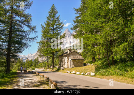 Malerische Aussicht auf das Val Ferret Tal am Fuße des Mont Blanc Massiv, mit einem kleinen Stein Kirche und Wanderer im Sommer, Courmayeur, Aostatal, Italien Stockfoto