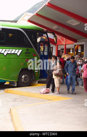 BANOS, Ecuador - 22. FEBRUAR 2014: Nicht identifizierte Personen am Busbahnhof mit dem Bus, der in der Rückseite und Imbissbuden auf der Seite Stockfoto