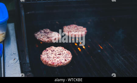 Burger Schnitzel vom Grill, Picknick mit Grillen im Freien. Schnitzel Grill gebraten auf Metallgitter. Die Person kochen Burger. Kochen Fleisch auf dem gr Stockfoto