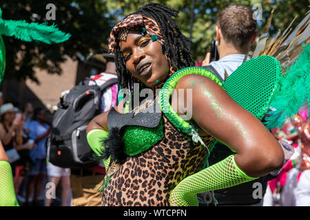 Eine Parade goer in einem Leopard Print Top mit grünen gefiederten Flügel bei Notting Hill Carnival am Montag, den 26. August 2019 gekleidet Stockfoto