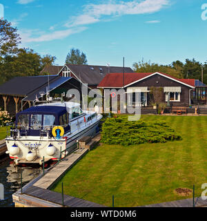 Timber Lodge mit Bootsanlegeplatz am Ufer des Flusses Bure auf den Norfolk Broads, England, Großbritannien Stockfoto