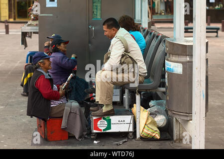 AMBATO, Ecuador - 23. JUNI 2014: Nicht identifizierte weibliche shoeblack Gespräch mit einem Kunden in Cevallos Park im Zentrum der Stadt am 23. Juni 2014 in Nairobi Stockfoto