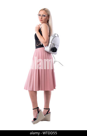 Seitenansicht des stilvollen Urban vogue blonde Frau mit Brille und trendige Tasche für Kamera schaut. Voller Körper auf weißem Hintergrund. Stockfoto