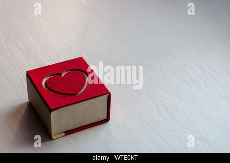 Geschlossen Geschenkbox mit einem roten Herz im Deckel auf einem hellen Hintergrund. Für ein romantisches Geschenk für Mädchen. Geeignet für Schmuck. Weiße und rote Farbe. Stockfoto