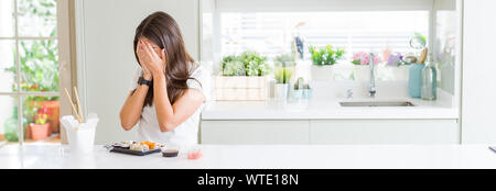 Weitwinkel Bild der schönen jungen Frau essen asiatische Sushi aus Lieferung mit traurigen Ausdruck für Gesicht mit den Händen und weinte. Depression con Stockfoto