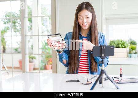 Schöne asiatische Einflussnehmer Frau Aufnahme Make-up Tutorial mit Smartphone Kamera sehr zufrieden zeigte mit Hand und Finger Stockfoto