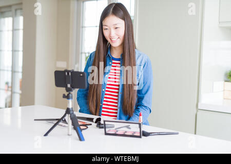 Schöne asiatische Einflussnehmer Frau Aufnahme Make-up Tutorial mit Smartphone Kamera mit einem glücklichen und kühlen Lächeln auf dem Gesicht. Glückliche Person. Stockfoto