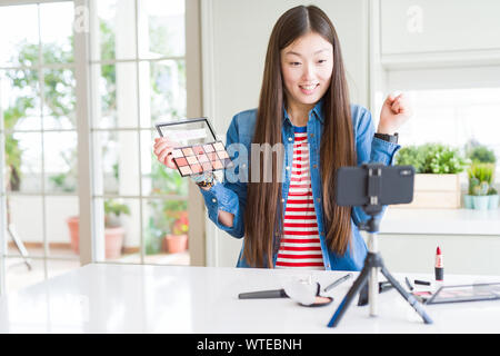 Schöne asiatische Einflussnehmer Frau Aufnahme Make-up Tutorial über Smartphone-kamera schreien stolz und feiern Sieg und Erfolg sehr aufgeregt, Stockfoto