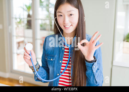 Schöne asiatische Frau prüfen health care mit Stethoskop tun ok Zeichen mit den Fingern, ausgezeichnete Symbol Stockfoto