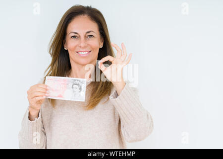 Mittleres Alter Frau mit 50 Pfund Bank Note über isolierte Hintergrund tun ok Zeichen mit den Fingern, ausgezeichnete Symbol Stockfoto