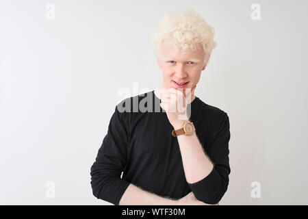 Junge albino blonder Mann in schwarzen T-Shirt stand über isoliert weißer Hintergrund mit Blick auf die Kamera sicher lächelnd mit verschränkten Armen und Han Stockfoto