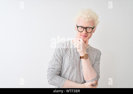 Junge albino blonder Mann tragen gestreifte T-Shirt und Brille über isoliert weißer Hintergrund in die Kamera schaut zuversichtlich lächelnd mit verschränkten Armen ein Stockfoto