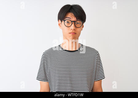 Chinesischer Mann mit Brille und Marine gestreiftes T-Shirt stehend über isoliert weißer Hintergrund gedrückt und für Not, Sorge und schrie wütend und Angst Stockfoto