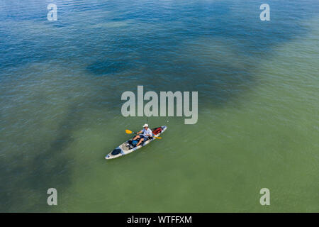 Man fischt von einem Kajak aus in seichten Küstengewässern nahe dem Dunedin Causeway, Florida. Stockfoto
